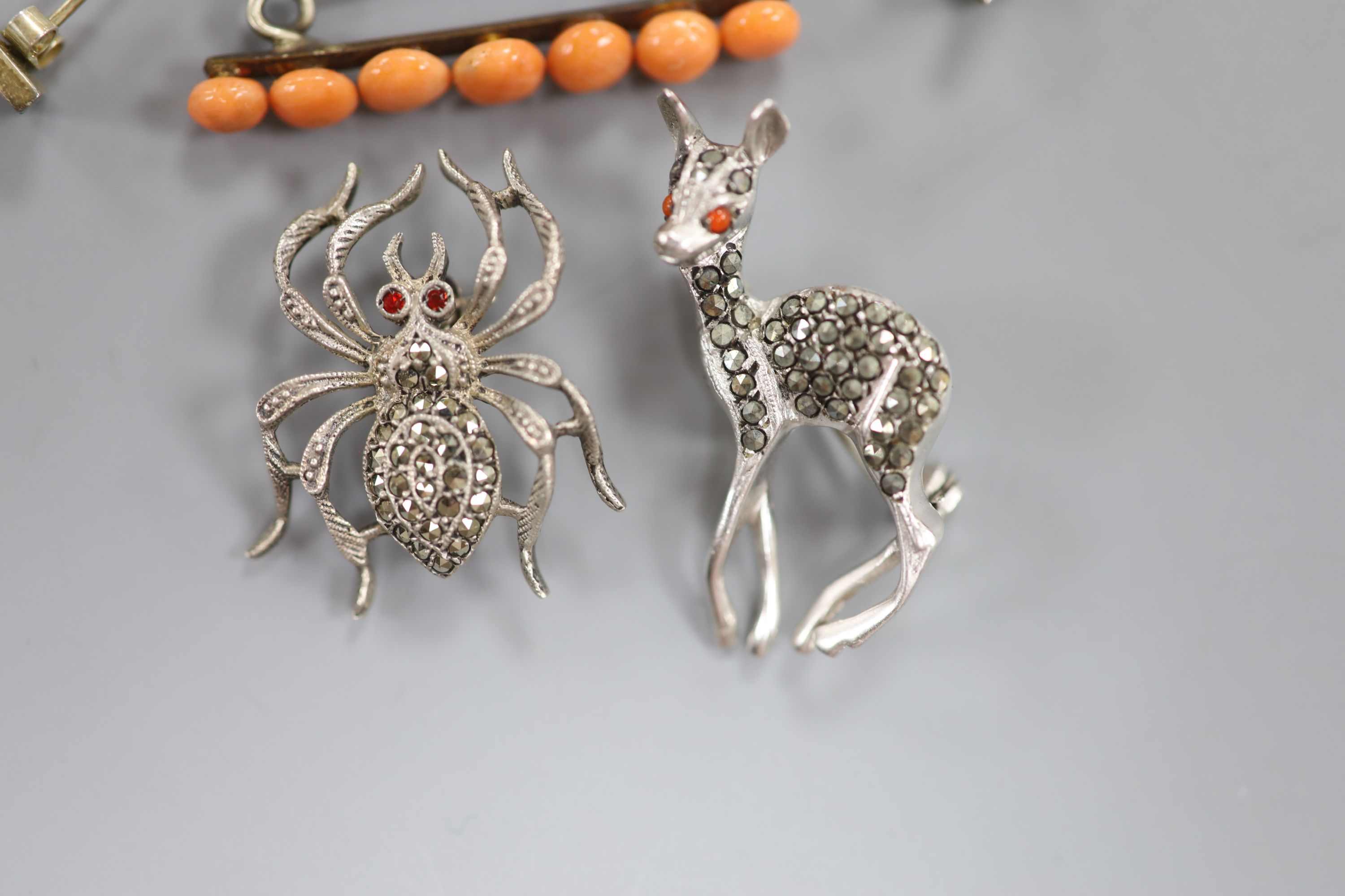 Two marcasite set brooches, a pair of earrings and a coral set brooch.